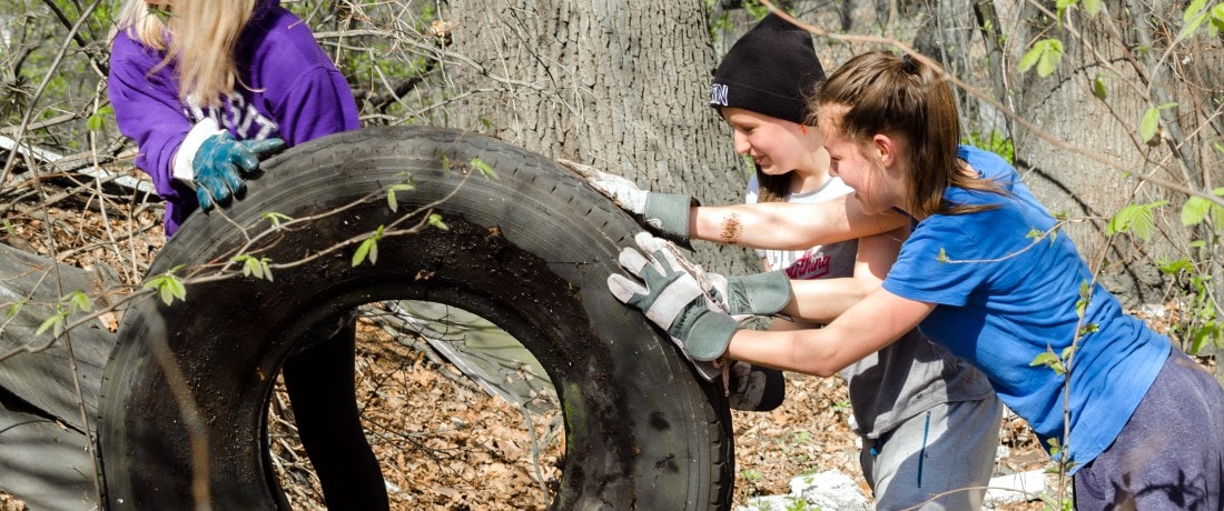 Dívky kutálejí pneumatiku mezi stromy