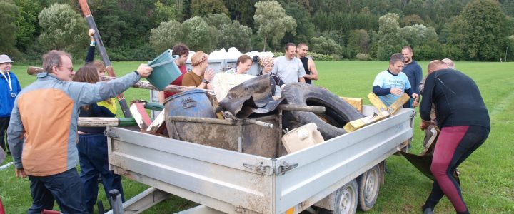 fotografie z čištění Vltavy 2022. Dobrovolníci hází sebraný odpad na přívěs za autem.